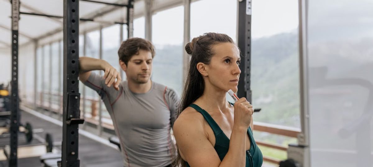 A fit couple engaged in gym exercises. Indoor workout with focus on fitness goals.